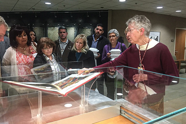 Sister Beth Mulvaney, Holy Cross Sister, shares a volume of The Saint John’s Bible Heritage Edition with guests. 