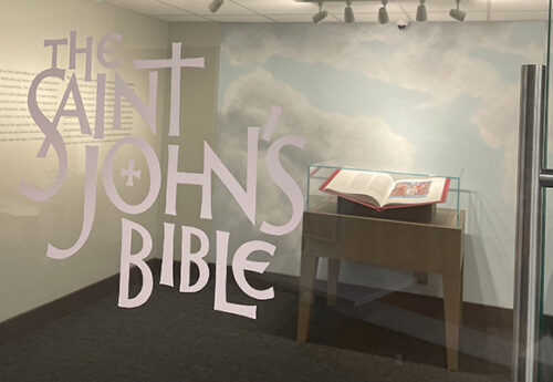 The Saint John's Bible is opened up behind a glass wall