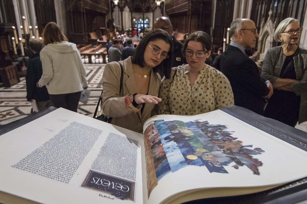 The Saint John's Bible lays open while two congregation members look at it at the Washington National Cathedral