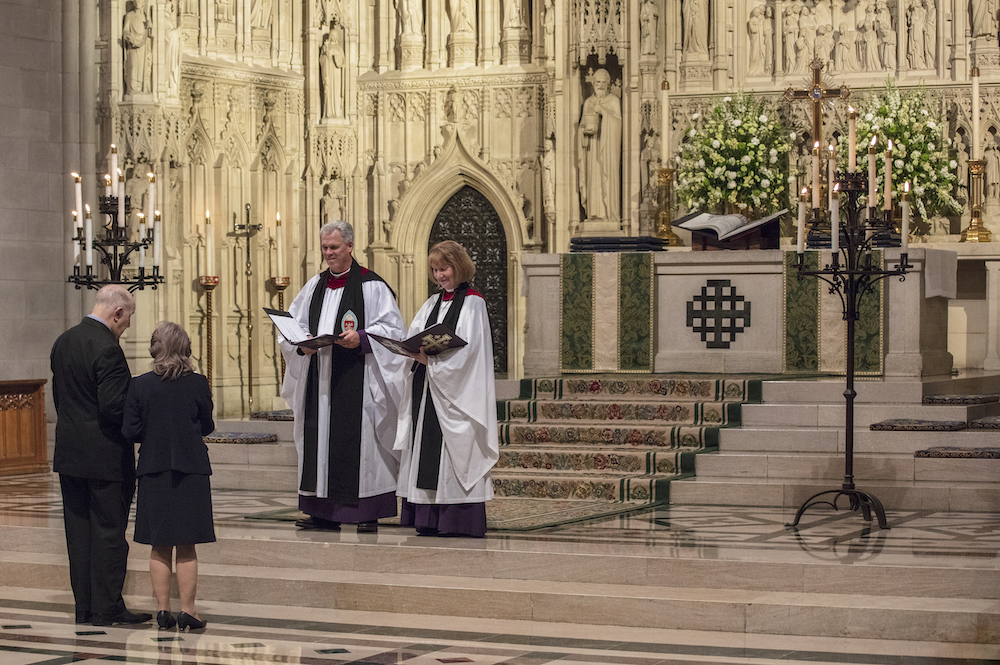 interior of washington national cathedral - a man and a woman face clergy members