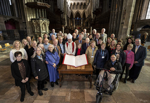 Photo: The entire Dedication Tour group poses for a photo at Salisbury Cathedral in front of a Heritage Edition. Dan Whalen is pictured to the left of the Bishop of Salisbury, the Most Reverend Stephen Lake.