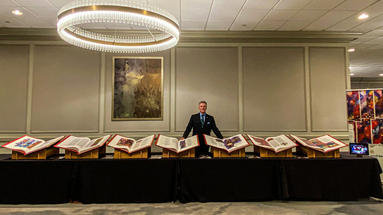 Director Brad Neary stands in front of all seven Heritage Edition volumes at the 2024 EPN Conference.