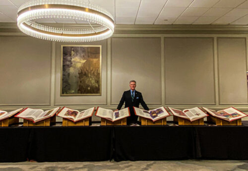 Director Brad Neary stands in front of all seven Heritage Edition volumes at the 2024 EPN Conference.