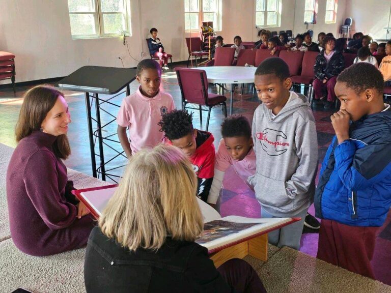 Docents from St. John’s Episcopal Church engage with a group of children as they gaze enthusiastically over the pages of The Saint John’s Bible Heritage Edition.